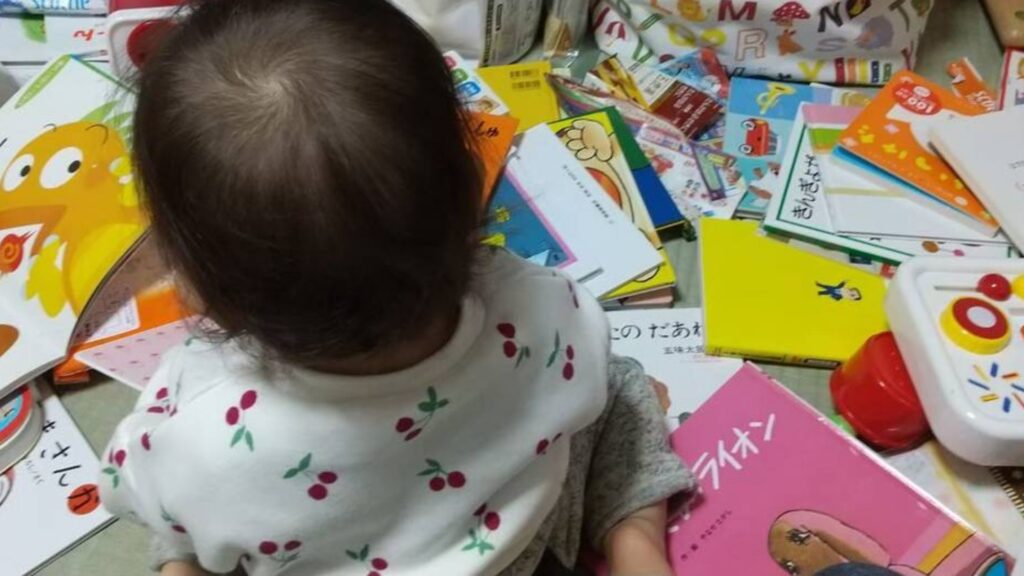本に囲まれて本を読む赤ちゃん