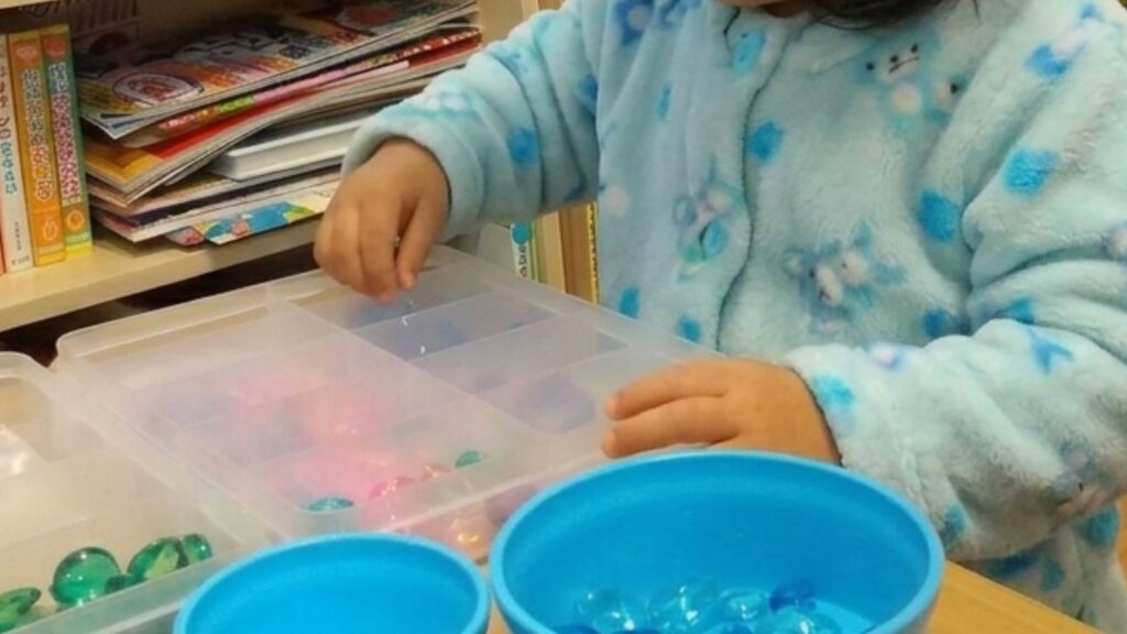 いろんな形や色のビーズを分ける子どもの手元