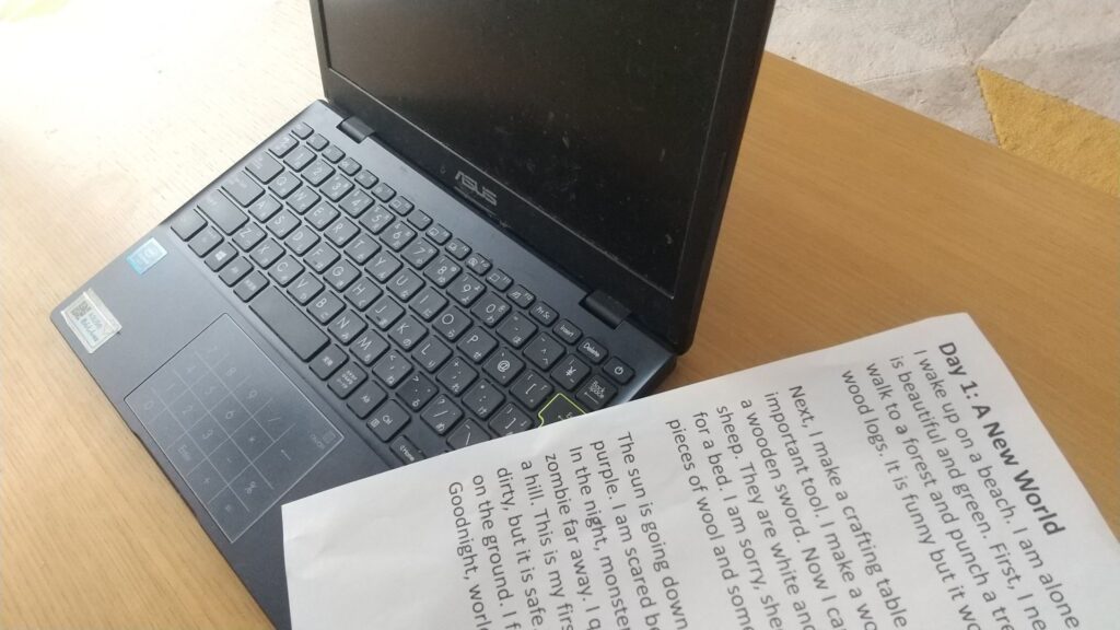 AIと作ったマイクラ物語の一話目が書かれたプリントと作成に用いたPC