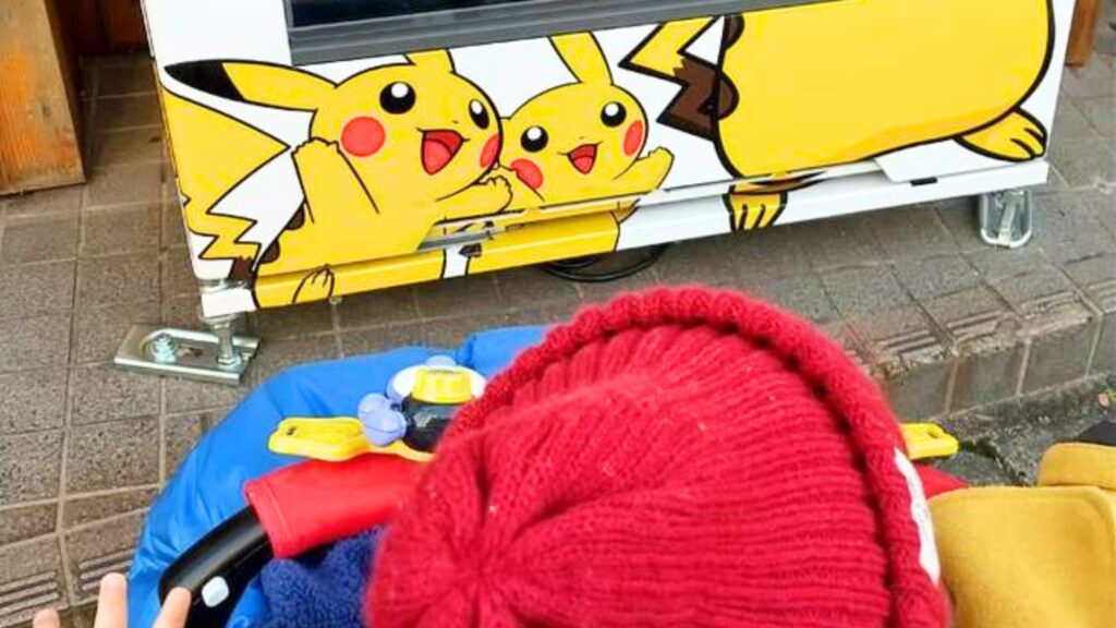 ポケモンのピカチュウが描かれた自動販売機とそれを指さす子ども